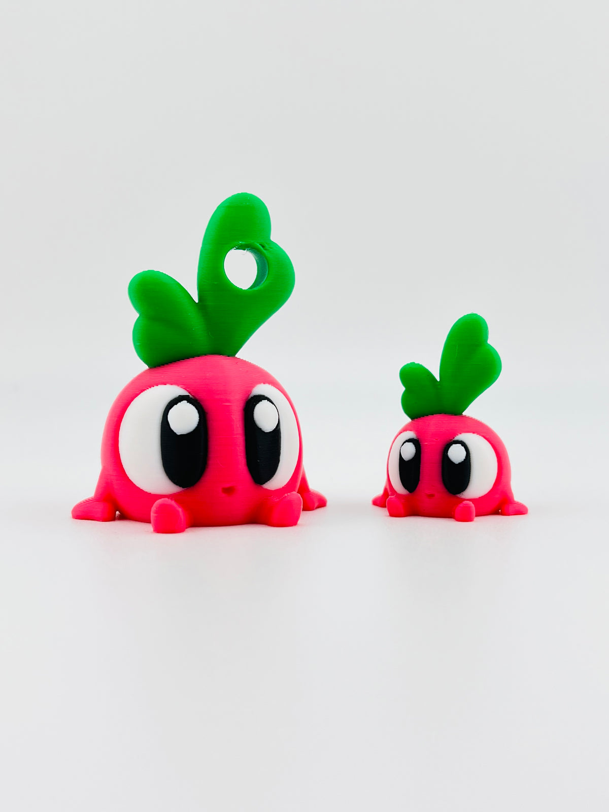 Pink radish fidget toys with green leaves and big eyes, in large and small sizes