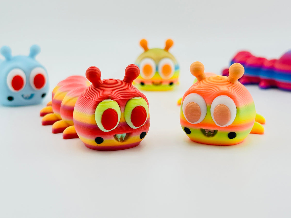 Big-eyed caterpillar fidget toys in rainbow, orange and pale blue