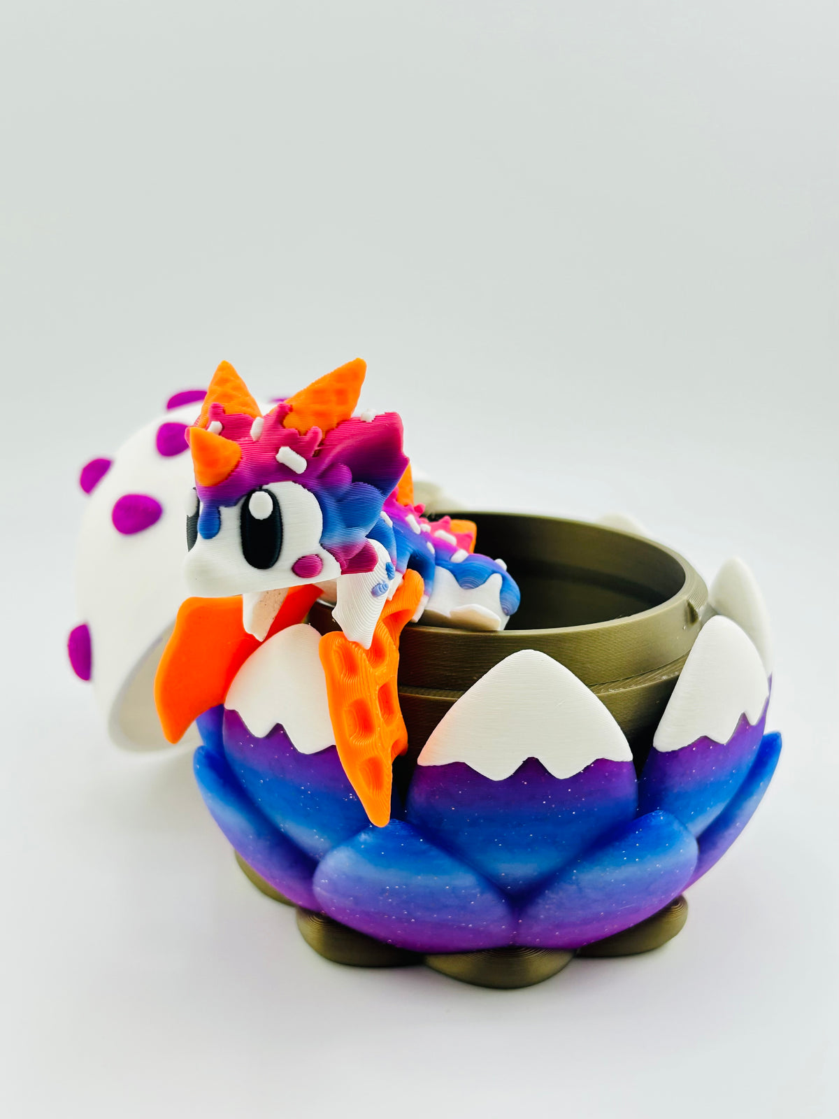 Purple and blue dragon egg with a colourful baby dragon hatching out