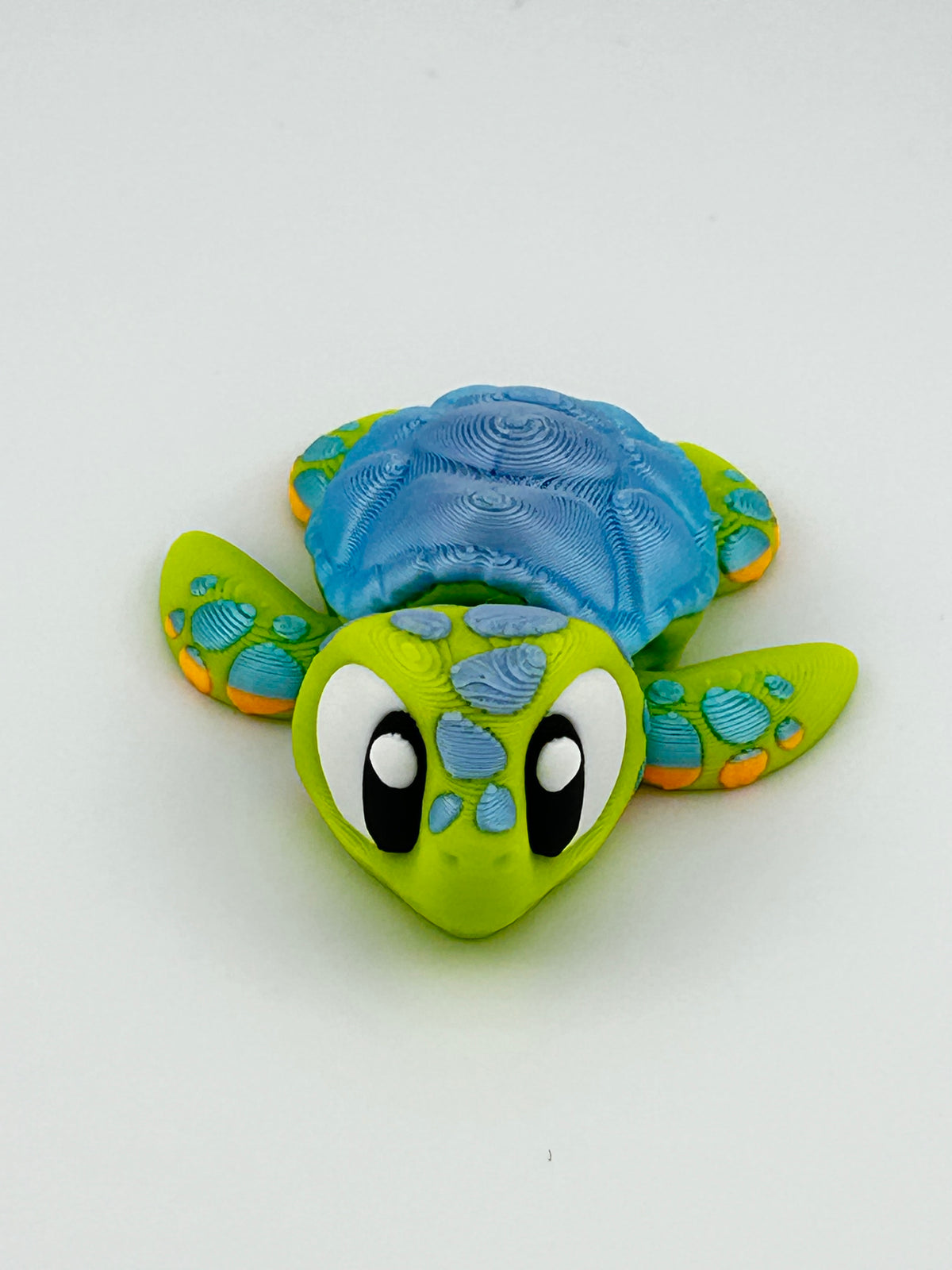 Green 3D printed sea turtle fidget toy with a blue shell and big eyes