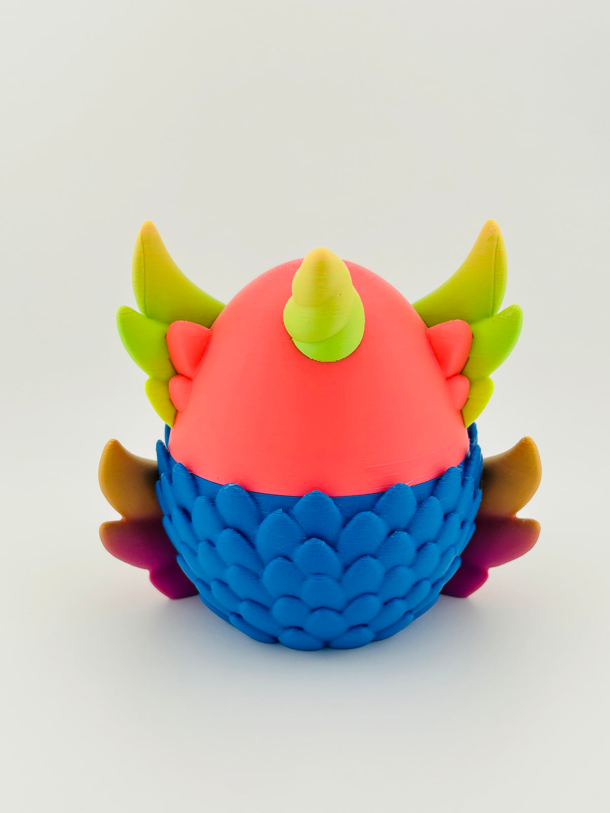 Coral pink and blue scaled dragon egg with horns and wings