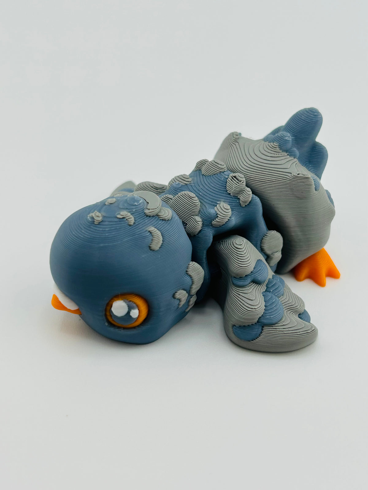 Blue-grey 3D printed pigeon fidget toy with an orange beak and feet
